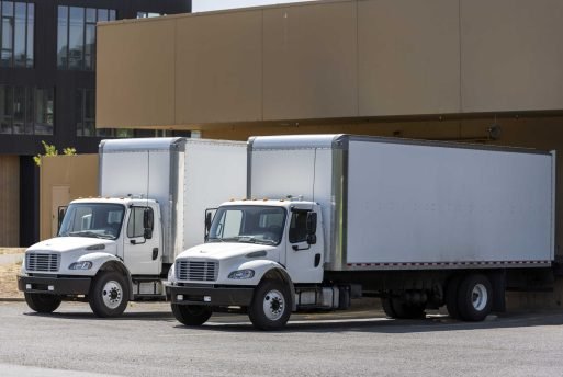 Small compact commercial industrial grade professional rigs semi trucks with long box trailers standing in warehouse dock loading different cargo for next timely delivery
